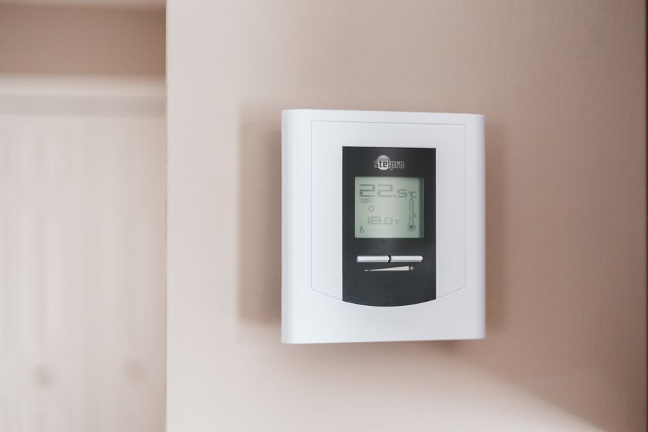 Vrouw configureert thermostaat voor energie-efficiëntie.